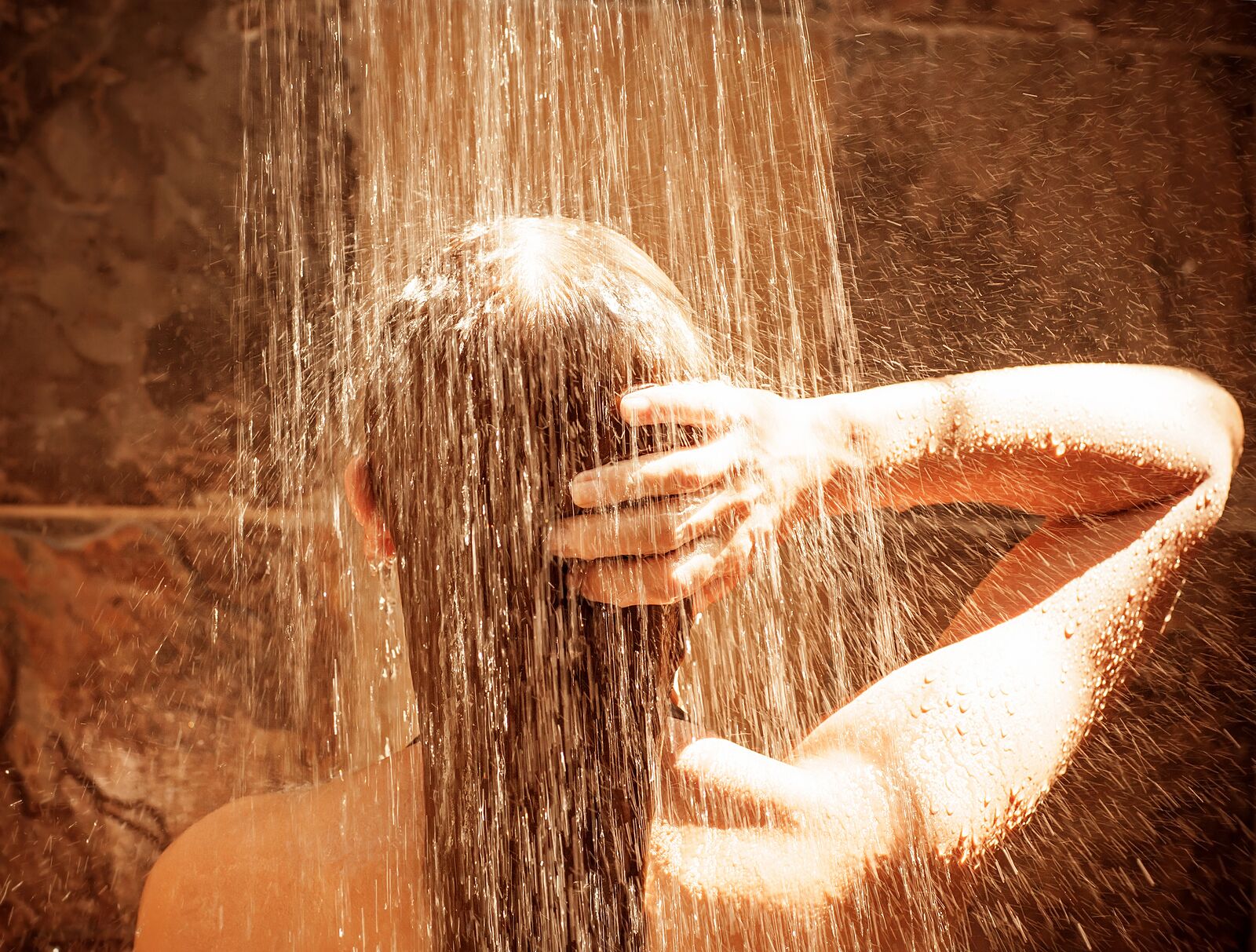 Rear view of young female take shower, enjoying sunlight and wat